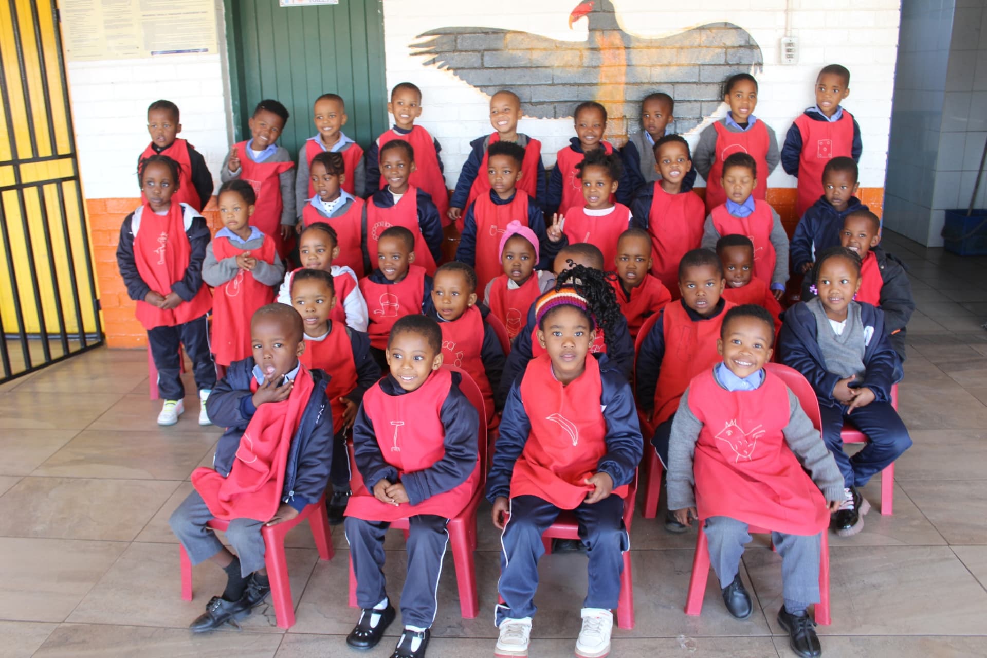 Younger class in red aprons gathered for a group photo in the hall