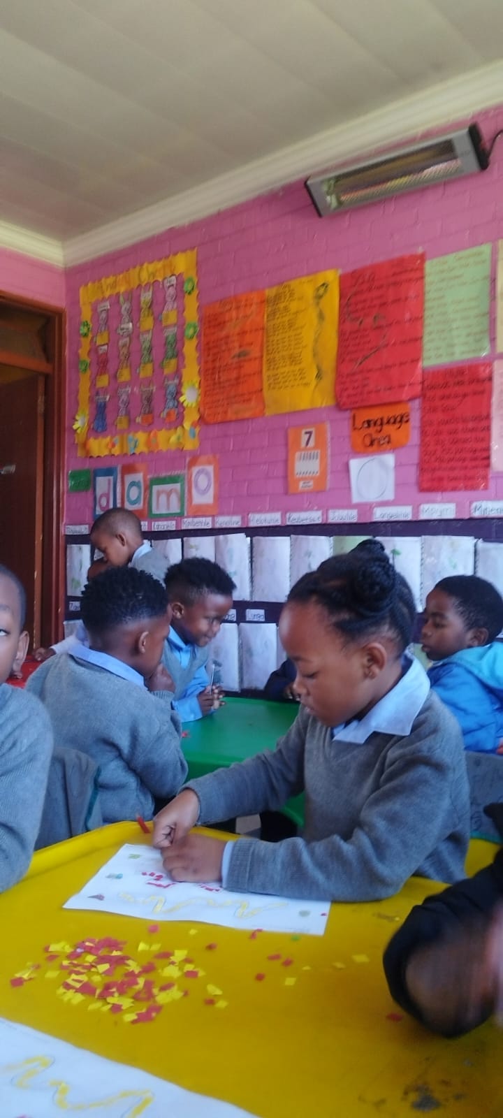 A classroom of learners busy with art and craft activities at colourful tables