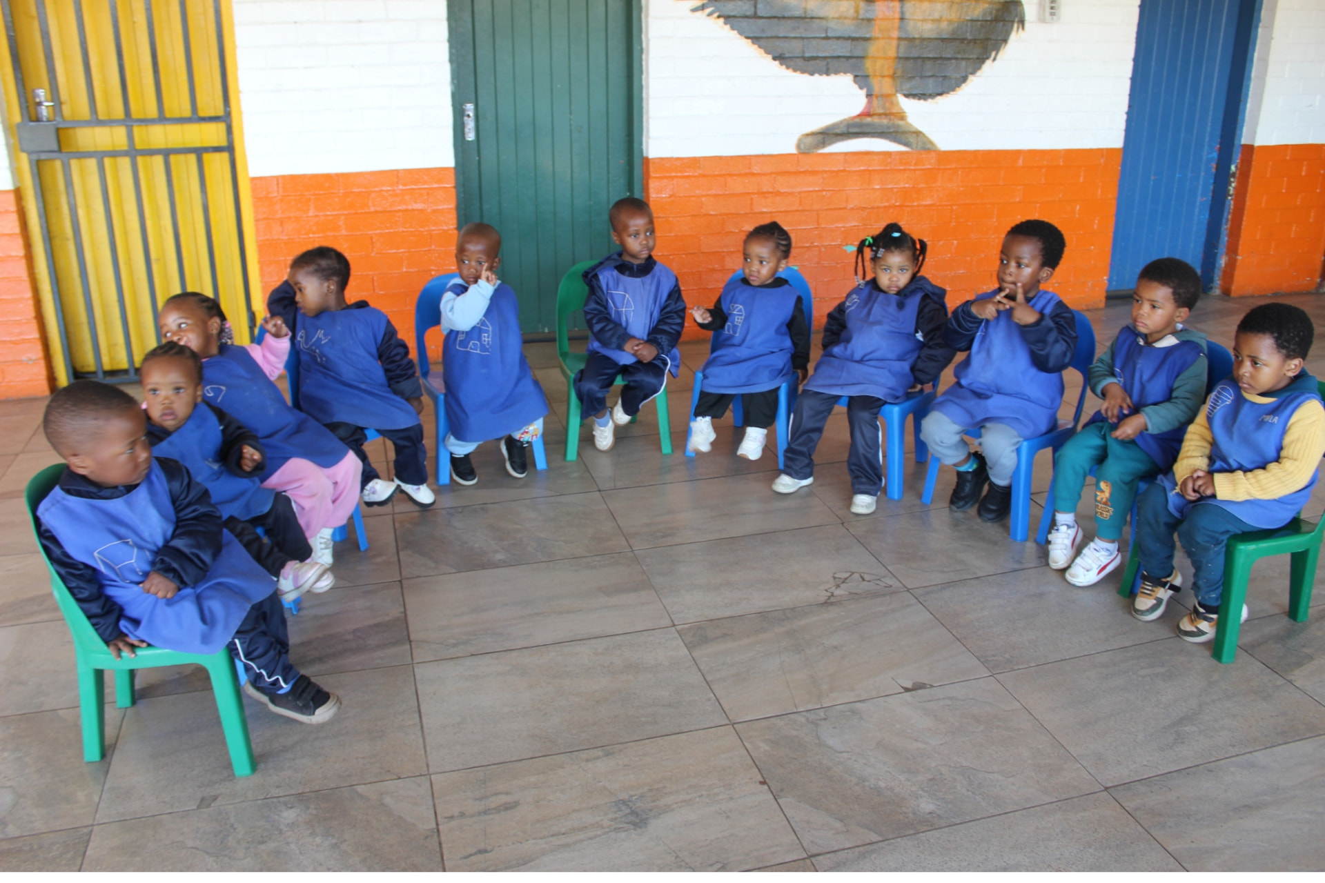 Toddlers in blue aprons seated in a circle during morning ring time