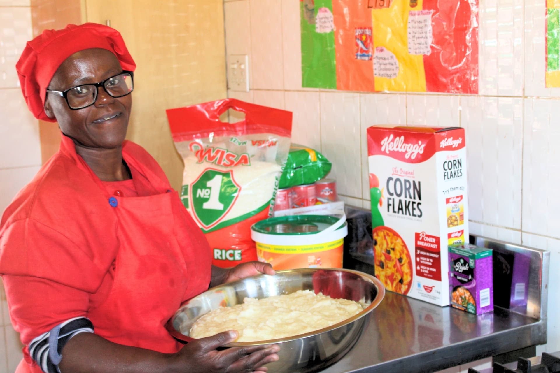 Matla Pre School cook holding a tray of freshly prepared pap in the school kitchen