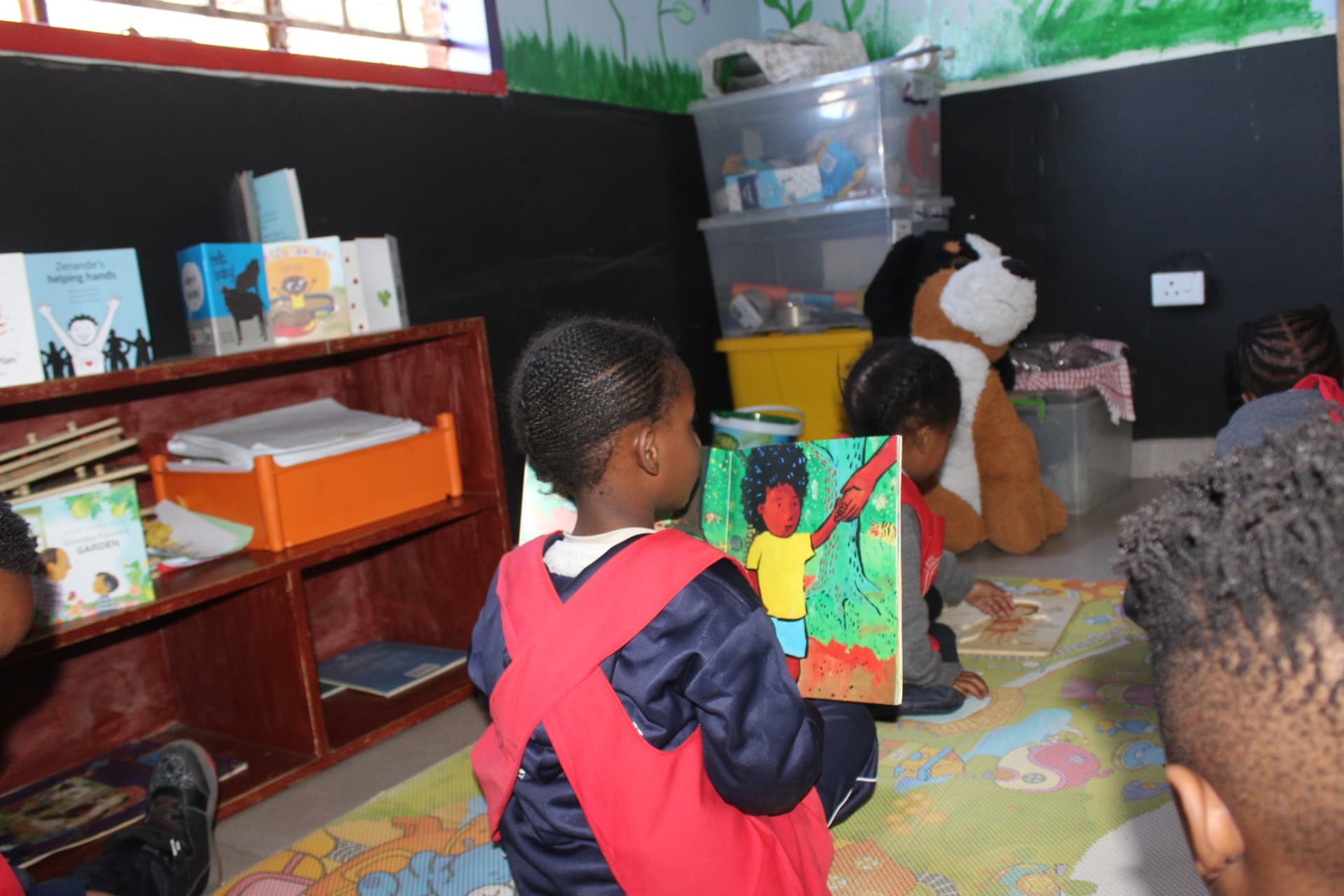 A learner holding up a storybook during quiet reading time at Matla Pre School
