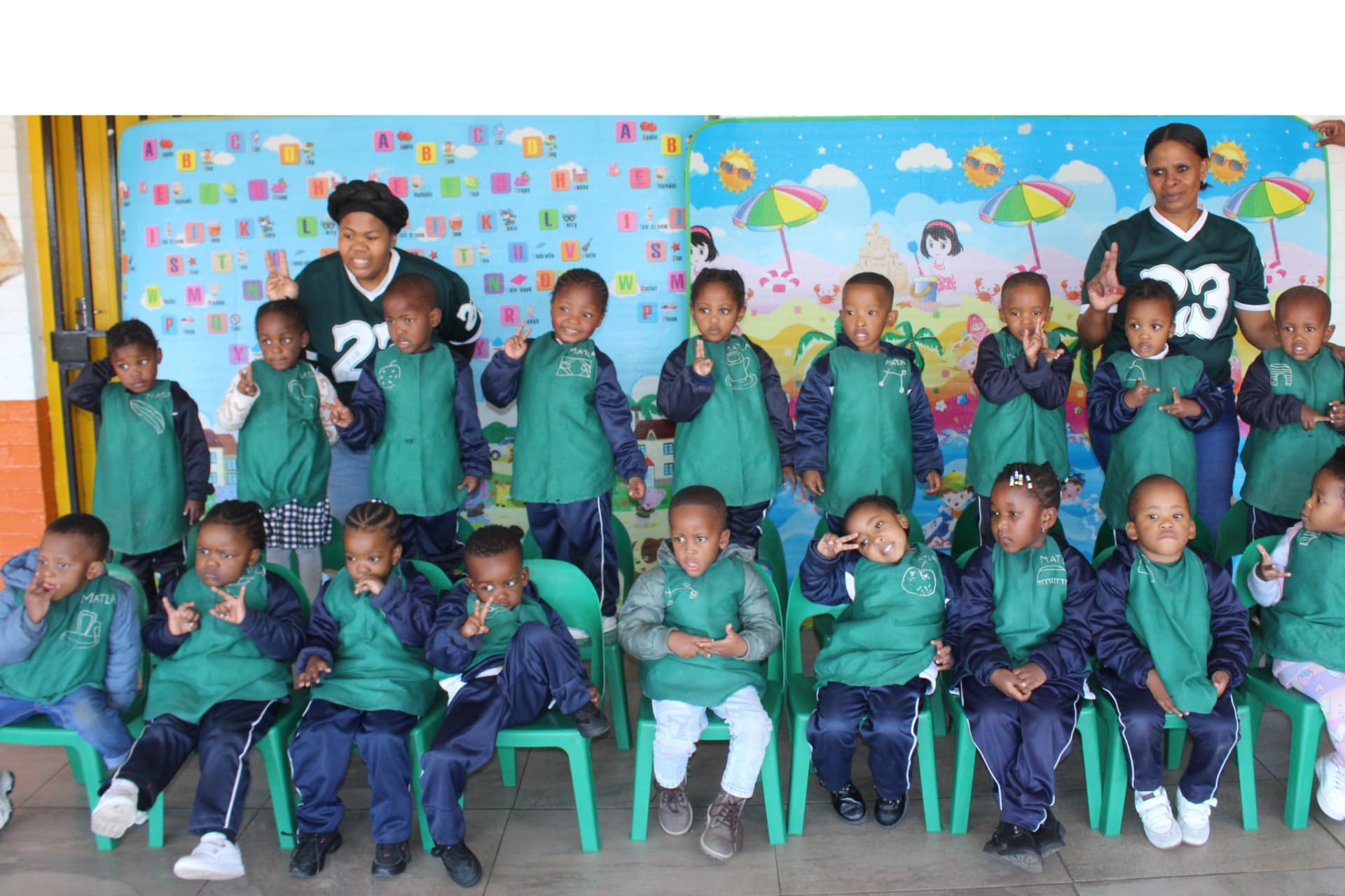 Matla Pre School middle group class in green aprons seated with their teachers