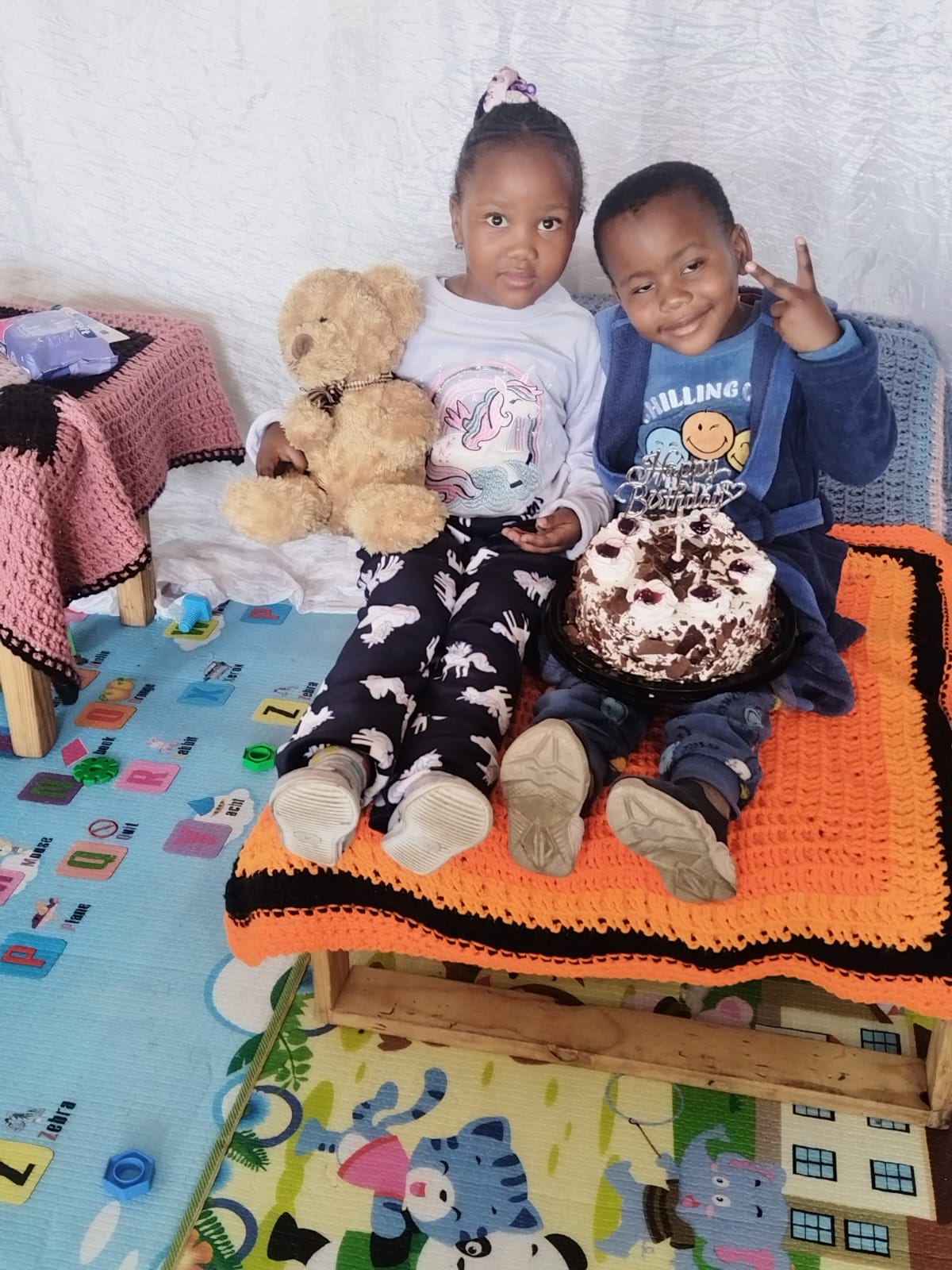 Two Matla learners celebrating a birthday with a chocolate cake and teddy bear