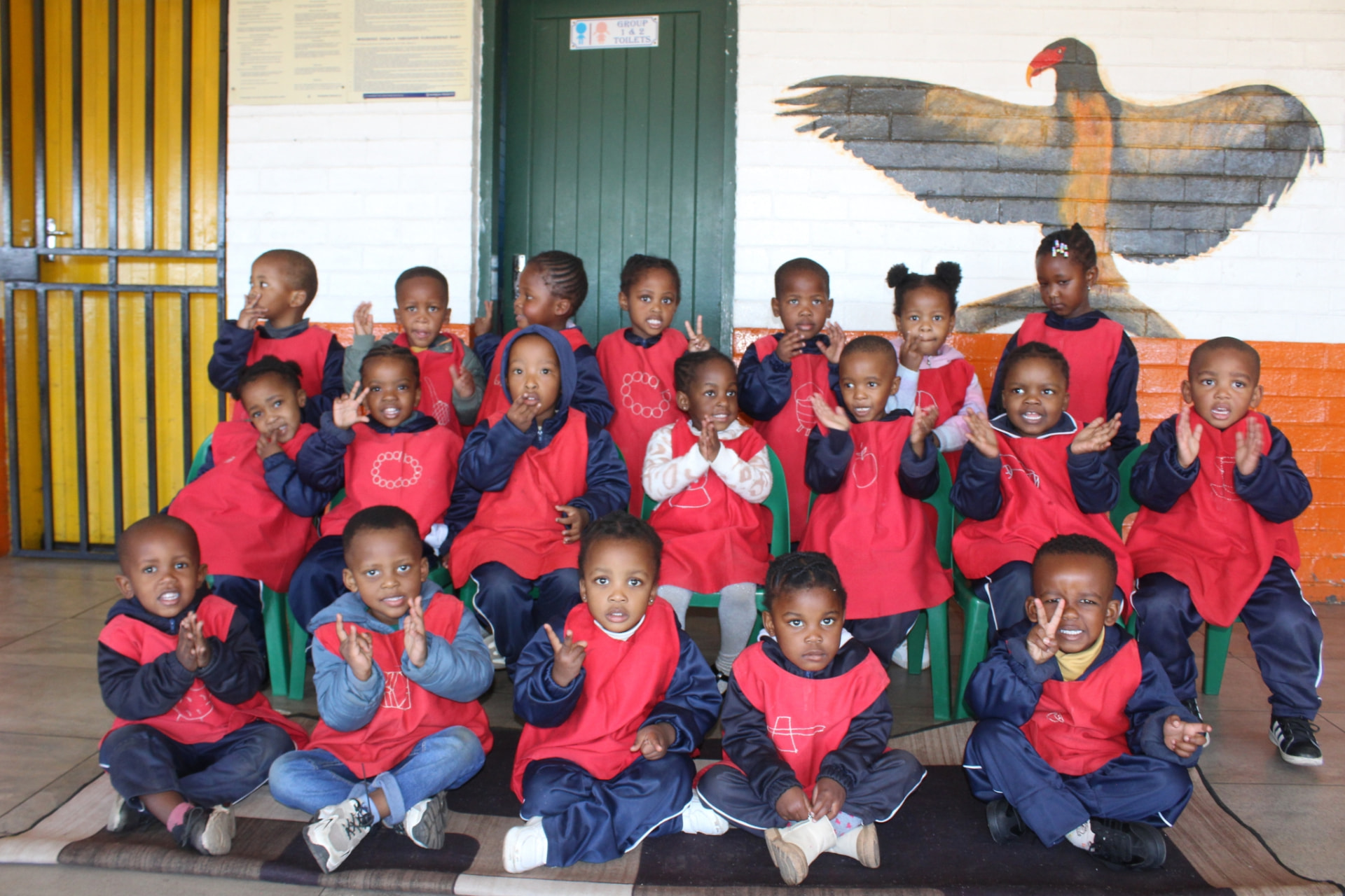 The red group waving and cheering for their class photo under the eagle mural
