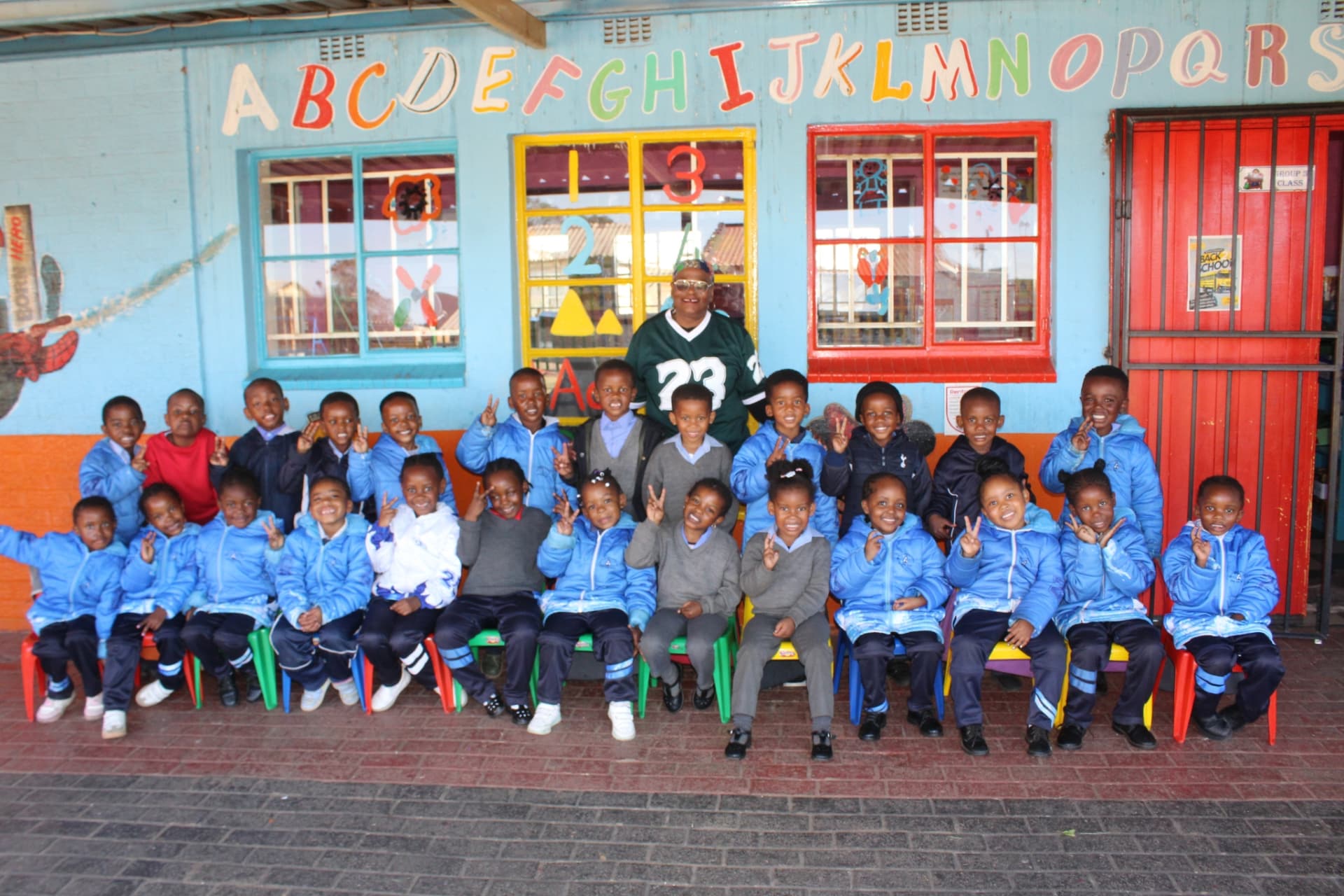 Matla Pre School learners and their teacher outside the classrooms in Mdeni, Soweto