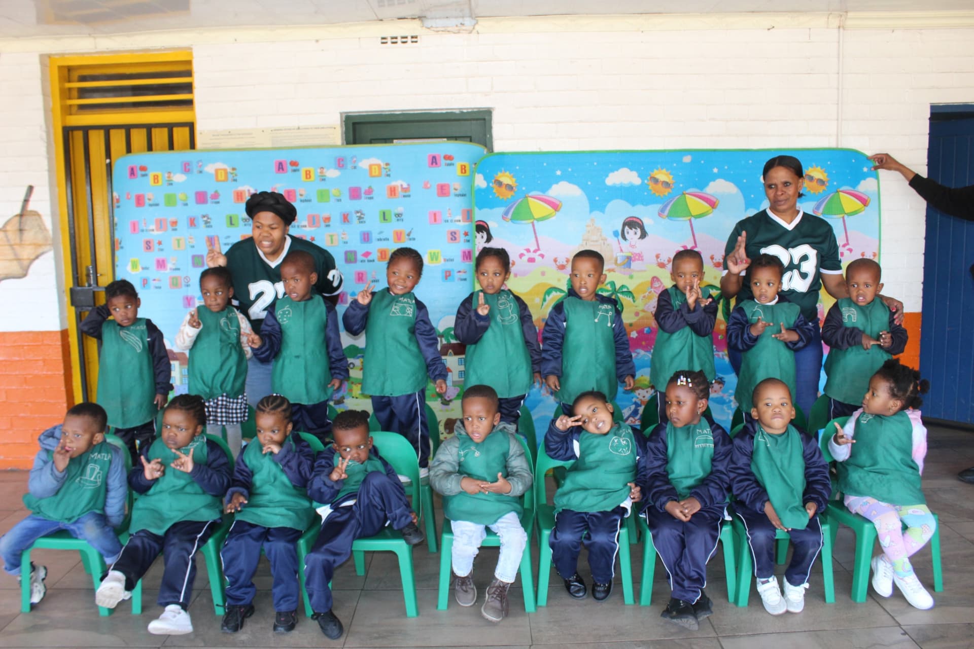 The green group class seated with their teachers for a class photo
